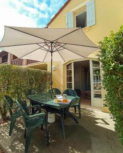 a table with an umbrella in front of a house at Maison de vacances pour détente dans résidence familiale avec prêt de vélos in Monflanquin