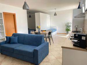 un soggiorno con divano blu e una cucina di GIOIA'S HOUSE a Custonaci