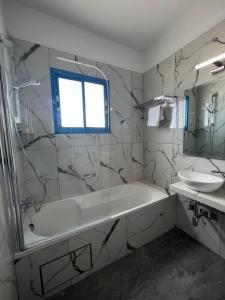 Kefalonitis Hotel Apartments في بافوس: حمام مع حوض استحمام ومغسلة