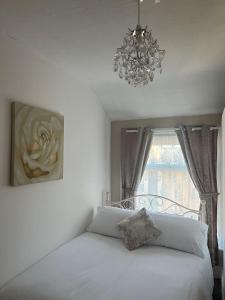 a bedroom with a bed with a chandelier and a window at New Derina Hotel in Blackpool