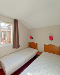 two beds in a room with a window at Maison de vacances pour détente dans résidence familiale avec prêt de vélos in Monflanquin