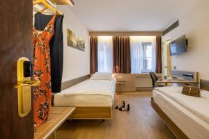 a hotel room with two beds and a desk at Hotel Alexander Zurich Old Town in Zurich +81 photos