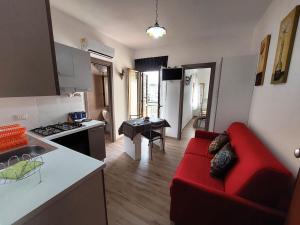 a living room with a red couch and a kitchen at Katia's Home in Scalea