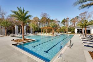 a large swimming pool with chairs and palm trees at Chic 1 and 2 Bedroom Apartments at Vintage Amelia Island next to Fernandina Beach in Fernandina Beach