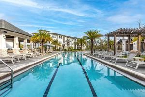 a swimming pool with chairs and palm trees in a resort at Chic 1 and 2 Bedroom Apartments at Vintage Amelia Island next to Fernandina Beach in Fernandina Beach