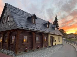 a house with a gambrel roof with a sunset in the background at Ferienhaus Sissi mit Whirlpool, Sauna u sehr ruhig in Großschönau
