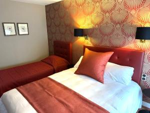 a bedroom with a bed with a red head board at Churchill Hotel Bayeux Centre in Bayeux