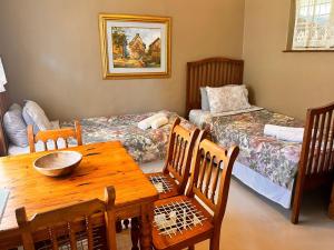 a dining room with a table and two beds at Farm stay at Rosemary Cottage on Haldon Estate in Bloemfontein
