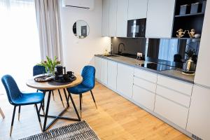 a kitchen with a wooden table and blue chairs at Apartamenty STUDIO M in Busko-Zdrój