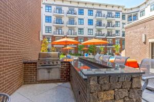 a patio with an outdoor grill and tables and umbrellas at Cozy and Bright Apartments at Marble Alley Lofts in Downtown Knoxville in Knoxville