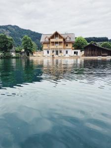 uma casa sentada em cima de uma grande massa de água em Villa Alma - a lakeside Boutique Hotel em Sankt Gilgen