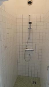 a white tiled shower with a hose in a bathroom at Bickersbed in Amsterdam