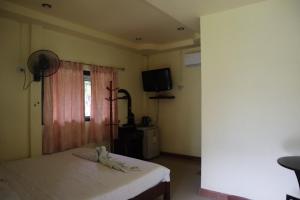 a bedroom with a bed and a tv and a window at ภูผาฮิลล์ รีสอร์ท in Lan Saka