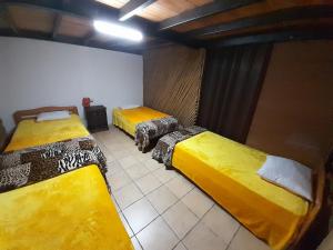 3 camas en una habitación con camas amarillas en Hostal Casa Búho, en Antigua Guatemala