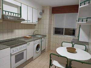 a kitchen with a table and a washing machine at Apartamento Puente in Portonovo