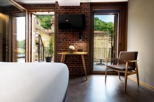 a room with a bed and a chair and a tv at Hotel Atari in Donostia-San Sebastián