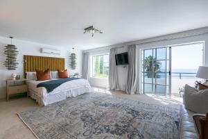 a bedroom with a bed and a large window at Bali and Eva Fresnaye. Luxurious 7 bedroom villa. Pool and grand patio in Cape Town