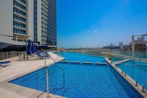 Superb Views & 36th Floor & Palm & Harbour View في دبي: مسبح كبير به ماء ازرق على مبنى