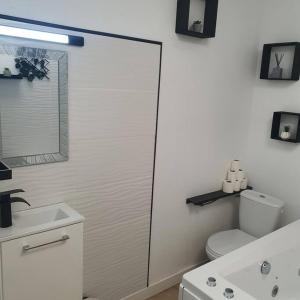 La salle de bains blanche est pourvue de toilettes et d'un lavabo. dans l'établissement studio avec balnéo proche mer, à Moriani-Plage