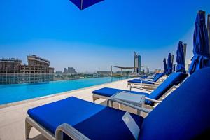 Superb Views & 36th Floor & Palm & Harbour View في دبي: مجموعة من كراسي الصالة الزرقاء ومسبح
