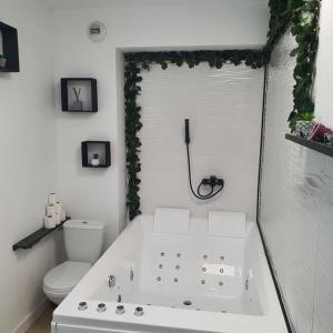 La salle de bains blanche est pourvue d'une baignoire et de toilettes. dans l'établissement studio avec balnéo proche mer, à Moriani-Plage