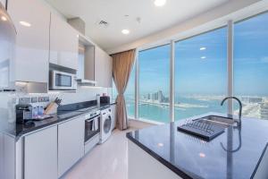 Superb Views & 36th Floor & Palm & Harbour View في دبي: مطبخ به أجهزة بيضاء ونافذة كبيرة