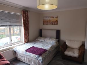 ein Schlafzimmer mit einem Bett, einem Stuhl und einem Fenster in der Unterkunft DACH Apartments - Cozy 3 bed Apartment in Hendon in Colindale