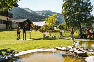 un grupo de personas de pie cerca de un estanque con una jirafa en Résidence Joséphine, en Châtel