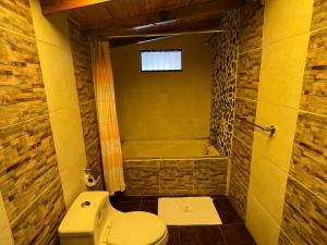 a bathroom with a toilet and a bath tub at CASONA LARA Lodge & Distillery in Caraz