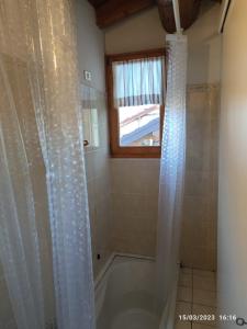 La salle de bains est pourvue d'une baignoire avec rideau de douche. dans l'établissement Casa Di Lena, à Gravedona