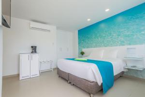 Dormitorio blanco con cama grande y pared azul en Hotel San Luis Place By Dorado, en San Andrés