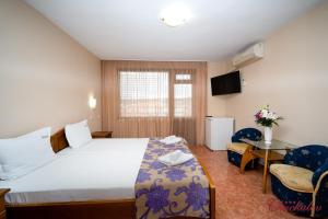 a hotel room with a bed and a table and chairs at Hotel Chuchulev in Sozopol