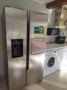 a stainless steel refrigerator in a kitchen with a washing machine at Casa a pié de playa de Cariño Doniños in Ferrol