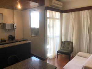 um quarto de hotel com uma cama e uma cadeira e uma janela em Condomínio Max Savassi Superior apto 1302 em Belo Horizonte