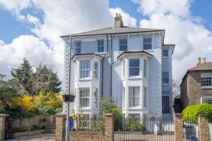 ein großes weißes Haus mit einem Zaun davor in der Unterkunft Stunning large Victorian Maisonette with sea view in Kent