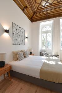 um quarto com uma grande cama branca e 2 janelas em LAA Studios em Coimbra