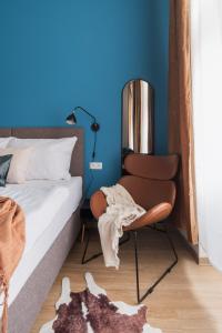 um quarto com paredes azuis e uma cama e uma cadeira em MIZU House by Prague Days em Praga