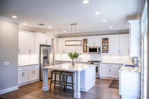 una cocina con armarios blancos y una mesa con taburetes en Bold Lab Studio 