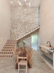a dining room with a table and chairs and a stone wall at Kuun Beek, hotel y centro holistico in Valladolid