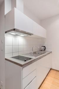 a white kitchen with a sink and a stove at MIZU House by Prague Days in Prague