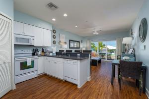 cocina con armarios blancos y sala de estar con mesa en Harbour House at the Inn 303, en Fort Myers Beach