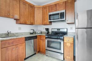 a kitchen with wooden cabinets and stainless steel appliances at Cozy N End 2BR steps from Harborwalk BOS-449 in Boston