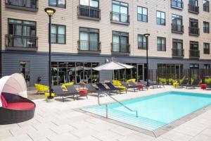 a pool in front of a building with chairs and an umbrella at Somerville 1BR w Gym Doorman nr Assembly Row BOS-228 in Somerville