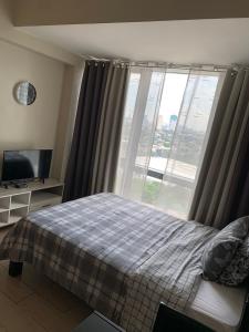 a bedroom with a bed and a large window at PJ PLACE TO STAY at One Eastwood Tower 1 at Unit 26J in Manila