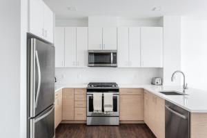 a kitchen with white cabinets and stainless steel appliances at 1BR w Gym WD Steps from Newtonville Train BOS-353 in Newton