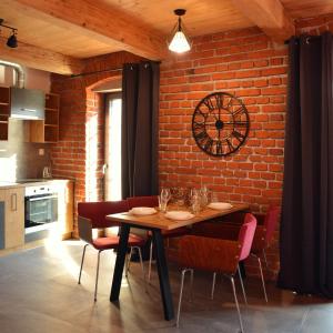 a dining room with a table and a clock on a brick wall at Rezidence Valcha in Sušice