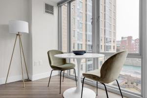 a table and two chairs in a room with large windows at E Cambridge 1BR w WD Gym steps from Train BOS-524 in Boston