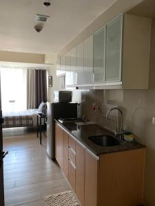 a kitchen with a sink and a room with a bed at PJ PLACE TO STAY at One Eastwood Tower 1 at Unit 26J in Manila