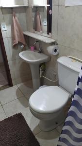a bathroom with a white toilet and a sink at 3 Kitnets in Rio das Ostras