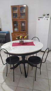 a white table with four chairs and a table with flowers on it at 3 Kitnets in Rio das Ostras